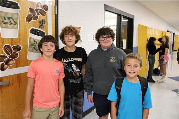 4 boys standing in school hallway